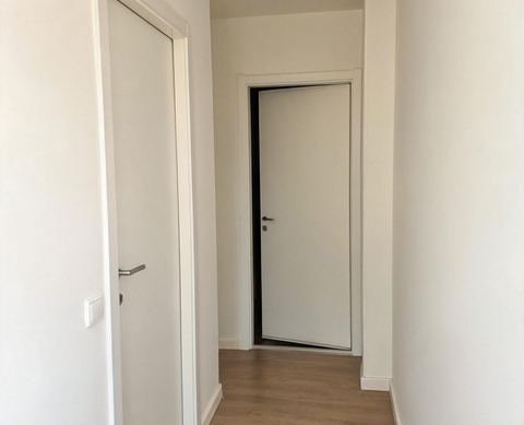Pasillo con puertas de paso lacadas en blanco, marcos blancos y suelo de tarima clara